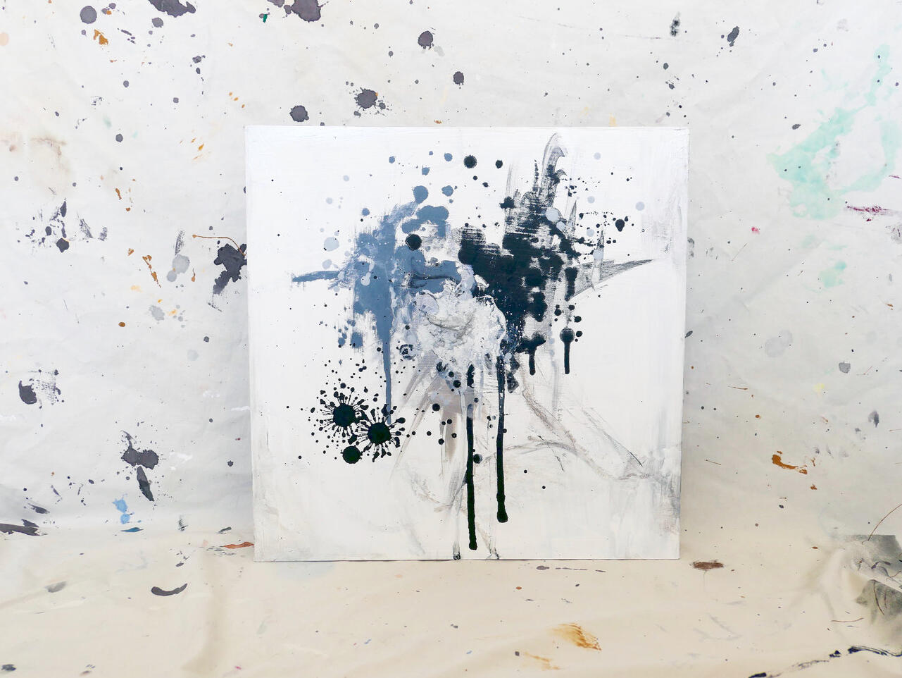 Abstract black and gray ink splatter painting on white canvas with expressive drips and splashes.