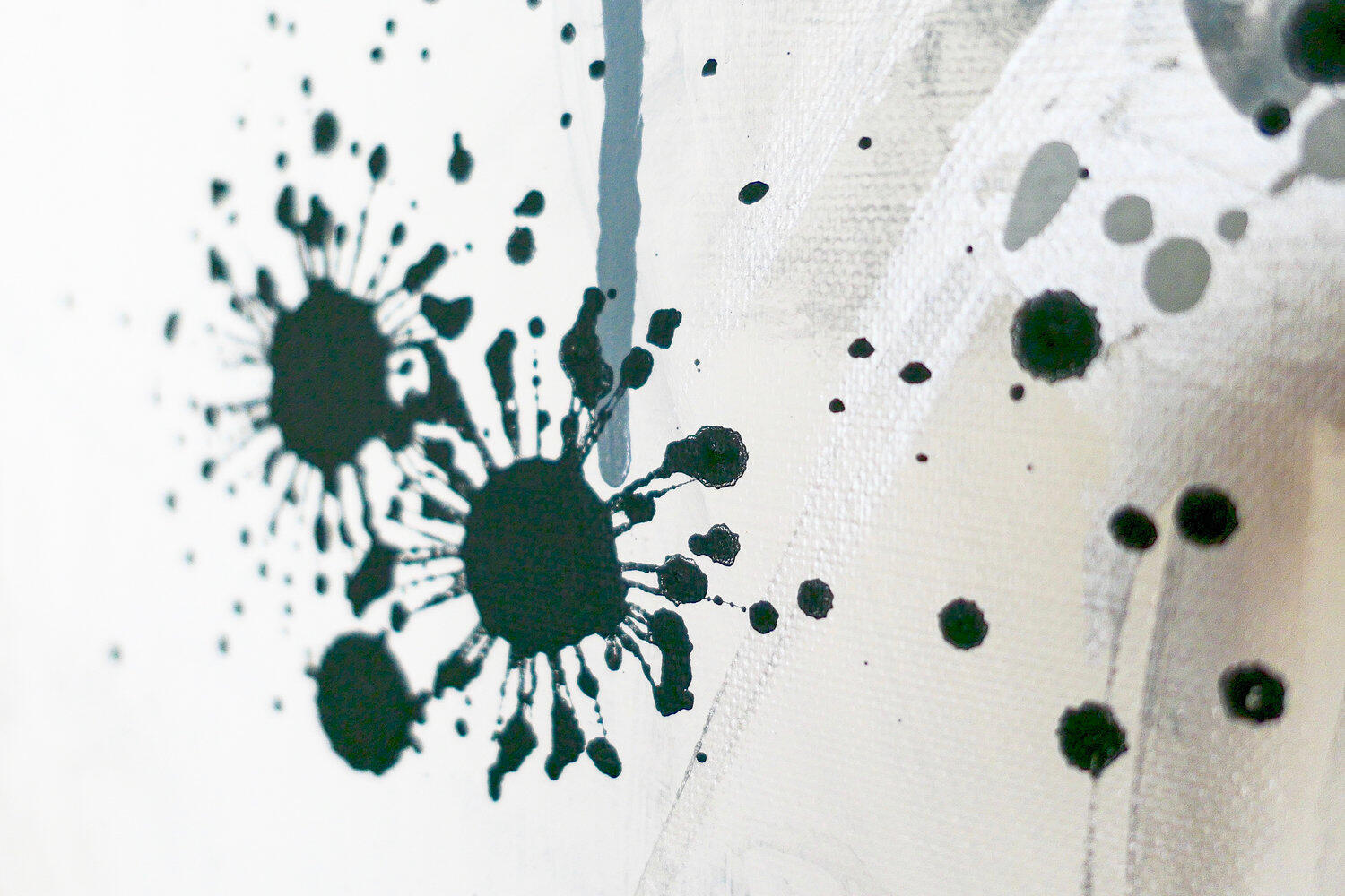 Abstract black and gray ink splatter painting on white canvas with expressive drips and splashes.